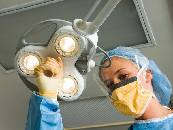 a woman in a surgical gown is operating a light fixture