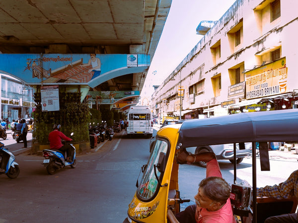 a woman driving a small yellow vehicle down a street