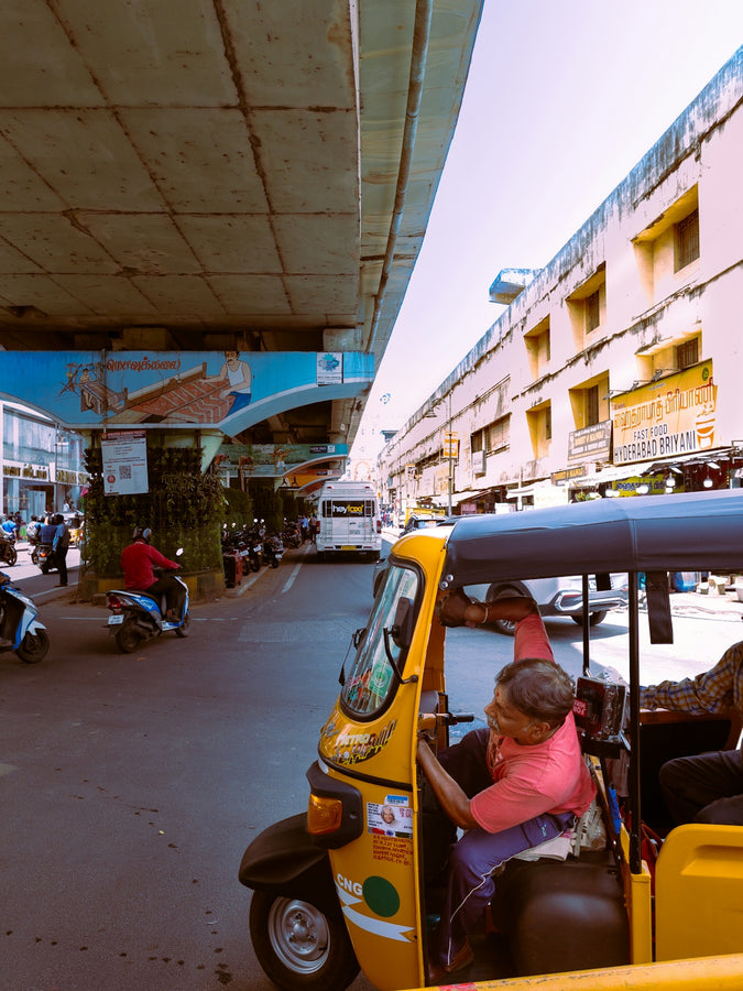 a woman driving a small yellow vehicle down a street