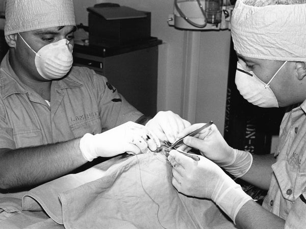 Two medical professionals perform a surgical procedure.