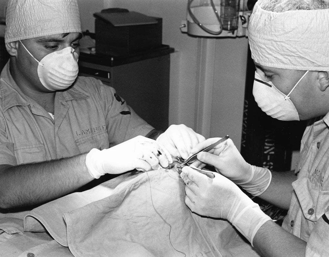 Two medical professionals perform a surgical procedure.