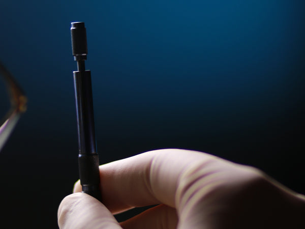 Gloved hand holding a surgical instrument.